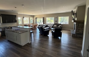 A spacious living area with a large island, dark wood flooring, and a fireplace.