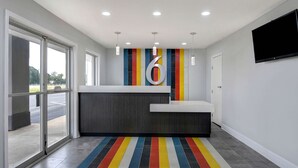 A reception area with a large number '6' on the wall, a counter, and a colorful striped carpet. - Studio 6 Meridian, MS - Bonita Lakes (Meridian)