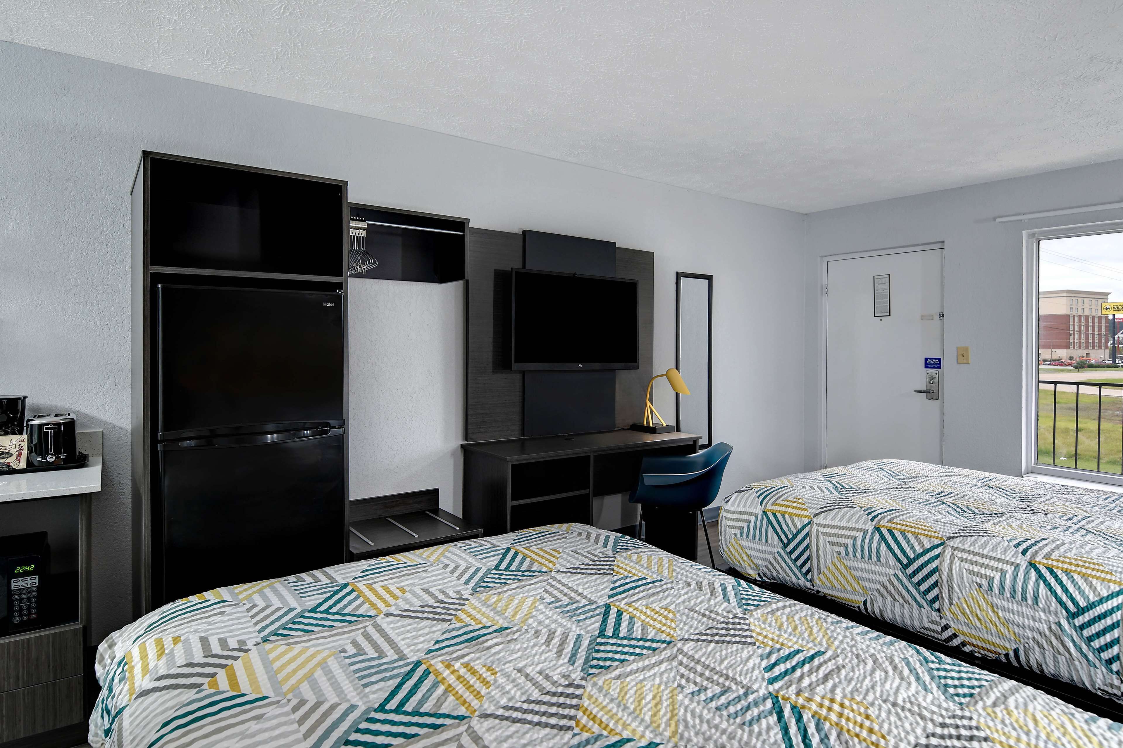 Hotelkamer met twee bedden, een bureau, een televisie, een koelkast en een raam met uitzicht.