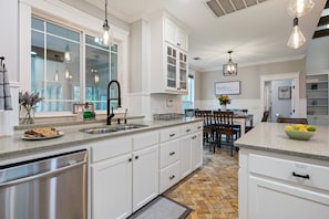 A modern kitchen with white cabinetry, a stainless steel dishwasher, and a granite countertop.