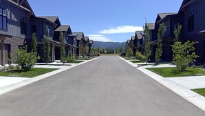 Una strada residenziale fiancheggiata da case moderne a due piani, con una carreggiata centrale e alberi regolarmente distanziati.