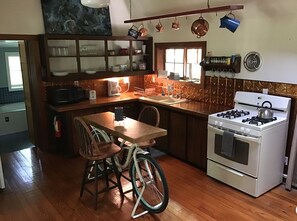 Kitchen features a central island with a sink and stove, surrounded by cabinetry and a copper-finish backsplash.