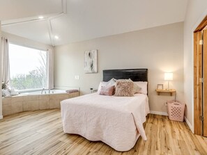A bedroom with a bed, a bedside table, a window seat, and a view of the outdoors. - Enchanting Memory Maker-Treetop Hideaway-Jacuzzi (Stigler)