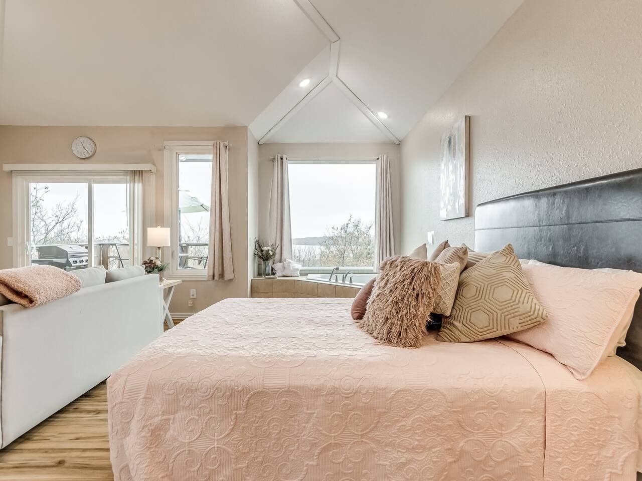 Een slaapkamer met een groot bed, een sofa en uitzicht op het omliggende landschap.