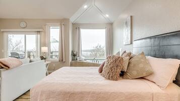 Een slaapkamer met een groot bed, een sofa en uitzicht op het omliggende landschap.