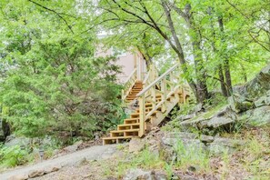 A wooden staircase leading up a rocky slope, surrounded by dense green foliage. - Private Ridge-Top Escape with Jetted Tub (Stigler)