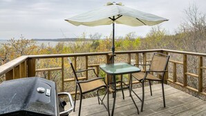 A deck with a table and chairs, a grill, and an umbrella. - Enchanting Memory Maker-Treetop Hideaway-Jacuzzi (Stigler)