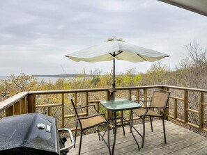 A deck with a table and chairs, a grill, and an umbrella. - Enchanting Memory Maker-Treetop Hideaway-Jacuzzi (Stigler)