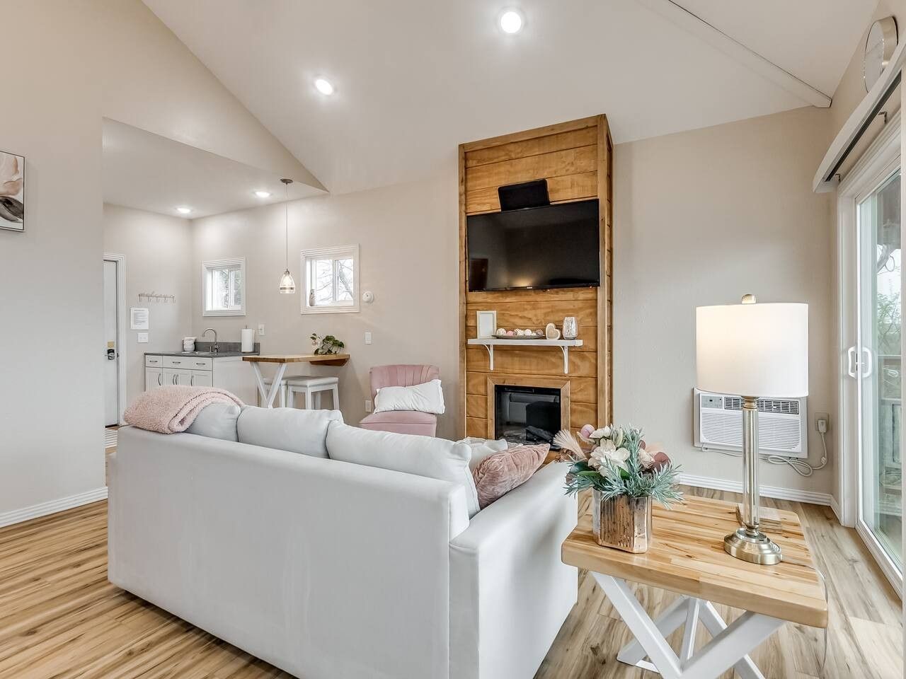 Una sala de estar moderna con un sofá blanco, una chimenea y un televisor montado en una pared de madera.