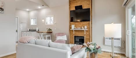 Una sala de estar moderna con un sofá blanco, una chimenea y un televisor montado en una pared de madera.