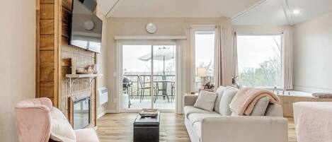 A spacious living area with a fireplace, a sofa, a coffee table, and a television mounted on a wooden wall.