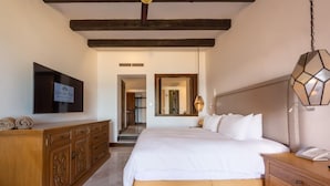 A bedroom with a large bed, wooden dresser, and a television mounted on the wall. - Beachfront Golf & Spa Paradise at Casa Del Mar (San Jose del Cabo)