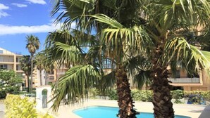 A pool area with palm trees and a building in the background.