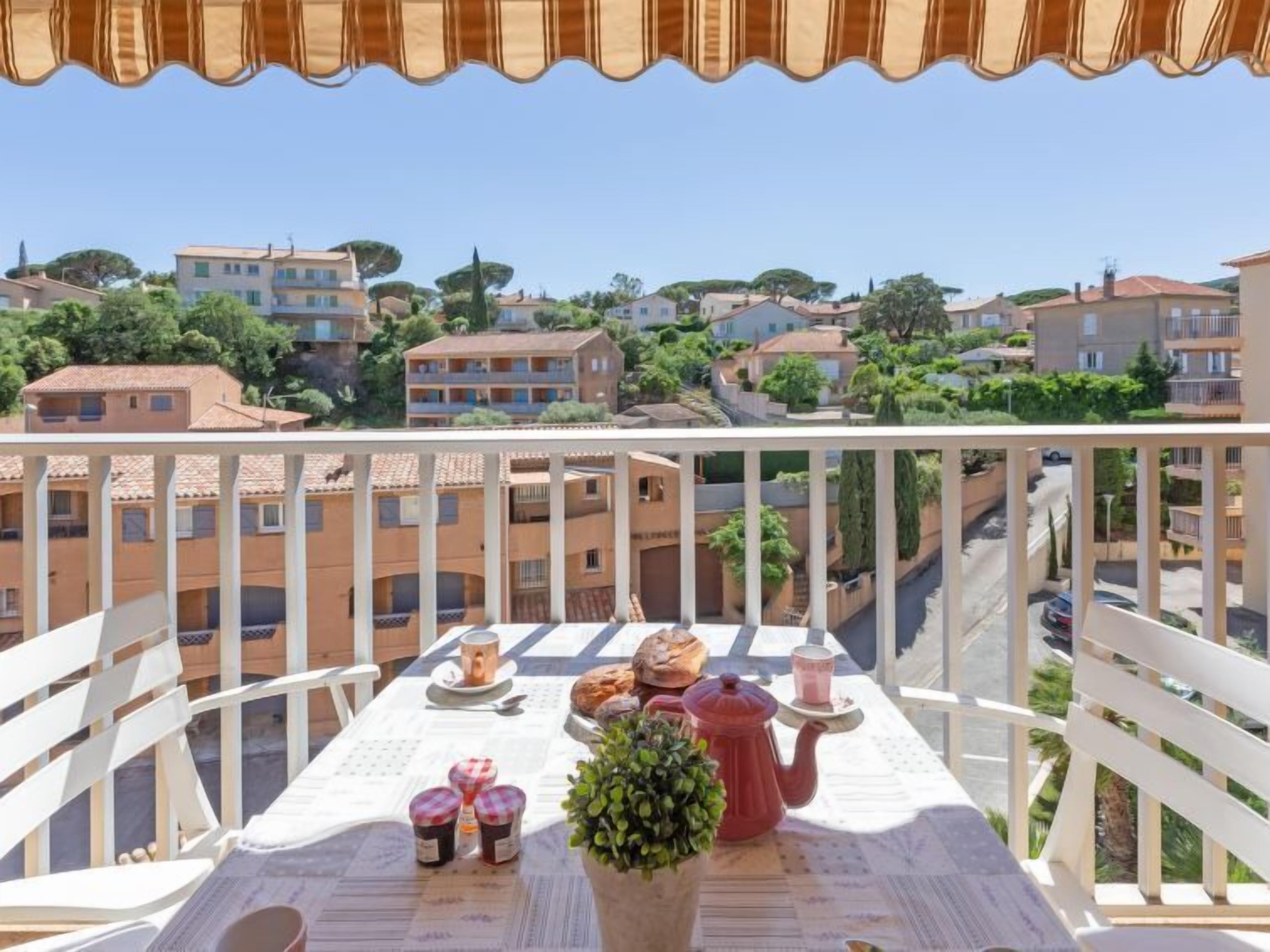 A balcony with a table set for breakfast, overlooking a residential area with terraced houses.