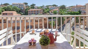 A balcony with a table set for breakfast, overlooking a residential area with terraced houses.