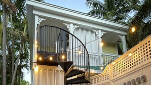 Une terrasse en bois avec des meubles d’extérieur, un escalier en colimaçon et des guirlandes lumineuses.