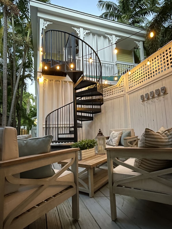 A wooden deck with outdoor furniture, a spiral staircase, and string lights.