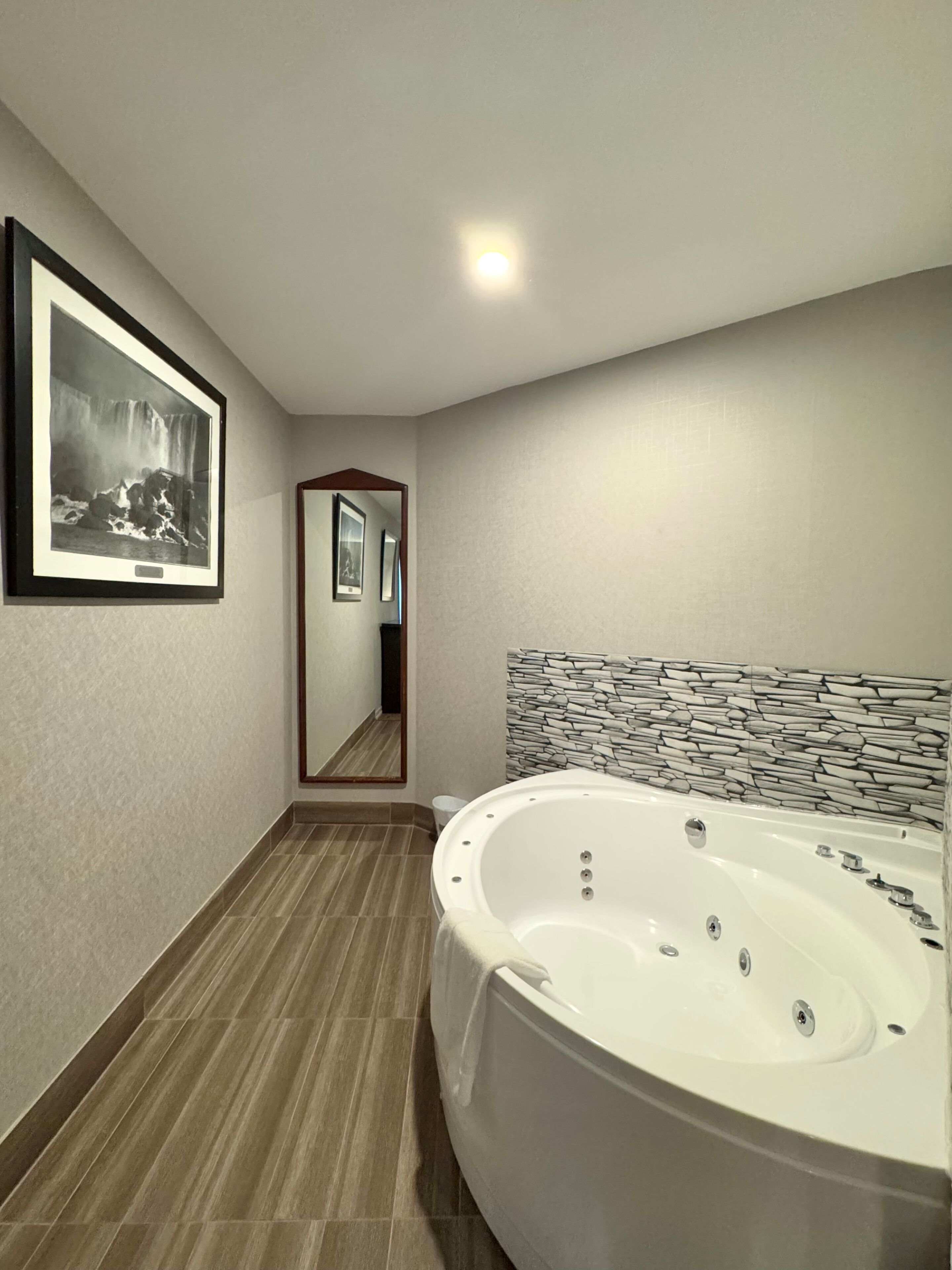 Un baño moderno con una bañera grande, una fotografía enmarcada en la pared y un espejo que refleja la habitación.