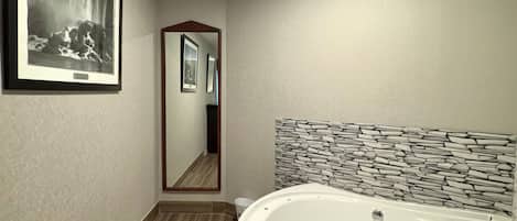 Un baño moderno con una bañera grande, una fotografía enmarcada en la pared y un espejo que refleja la habitación.