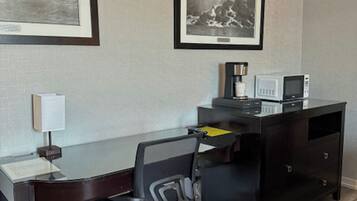 Una habitación de hotel con escritorio, silla y dos cuadros en la pared.