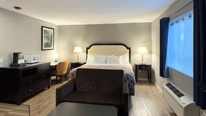 A hotel room with a bed, a desk, a chair, a coffee machine, a TV, and an air conditioner. - Big Bird Inn Wawa, SureStay Collection by Best Western (Wawa)