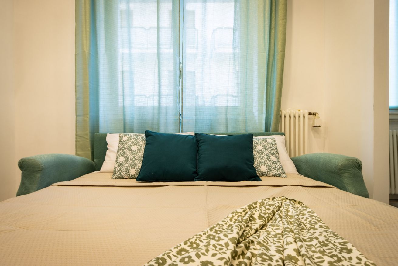 Un lit avec une couvre-lit à motifs, deux oreillers et une couverture.