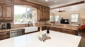 A spacious kitchen with a large island, wooden cabinets, granite countertops, and a built-in dishwasher.