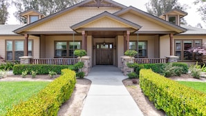 A two-story house with a front porch, a stone foundation, and a well-maintained garden.