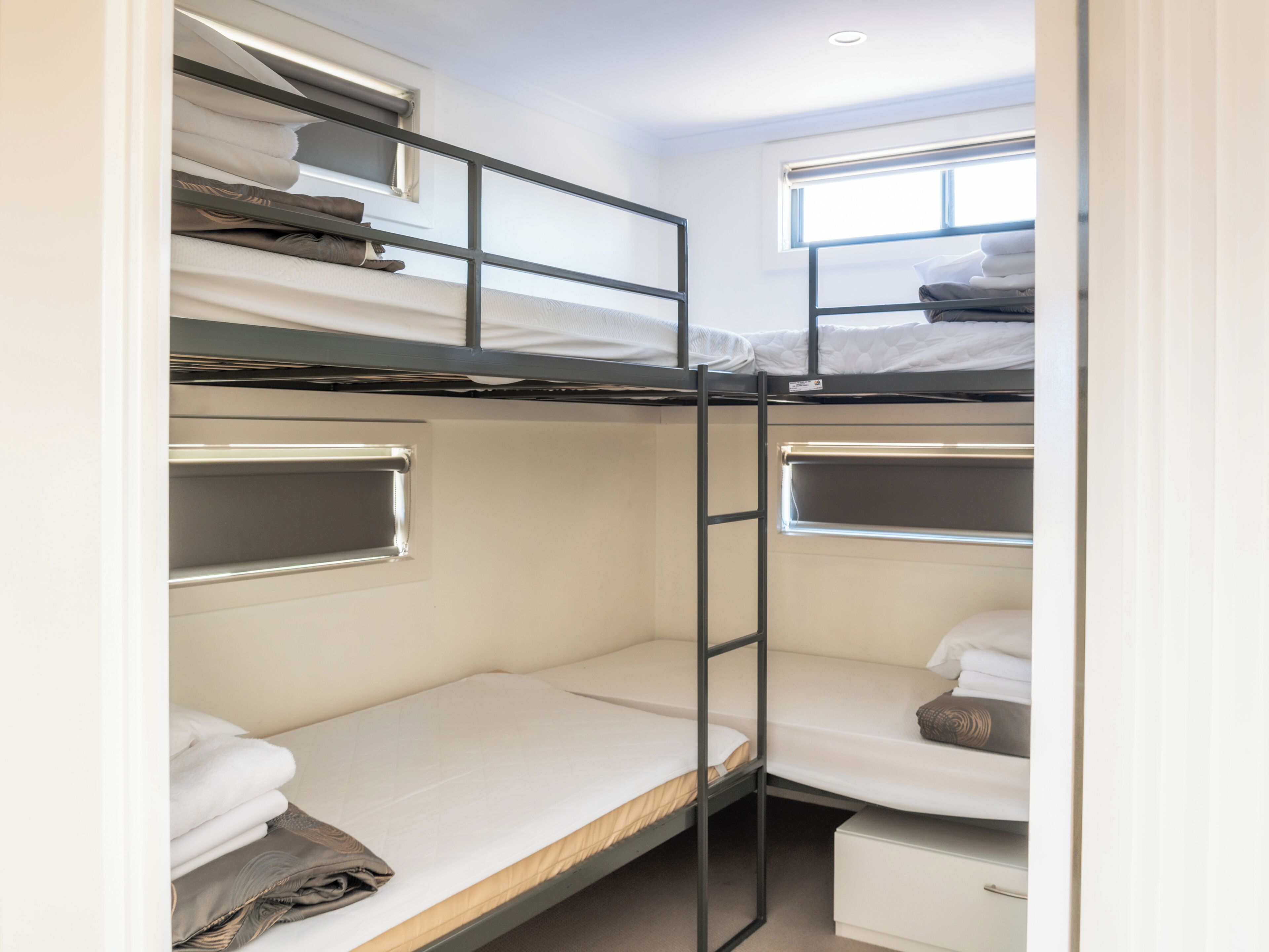 A bunk bed room with a window, a small desk, and a storage cabinet.