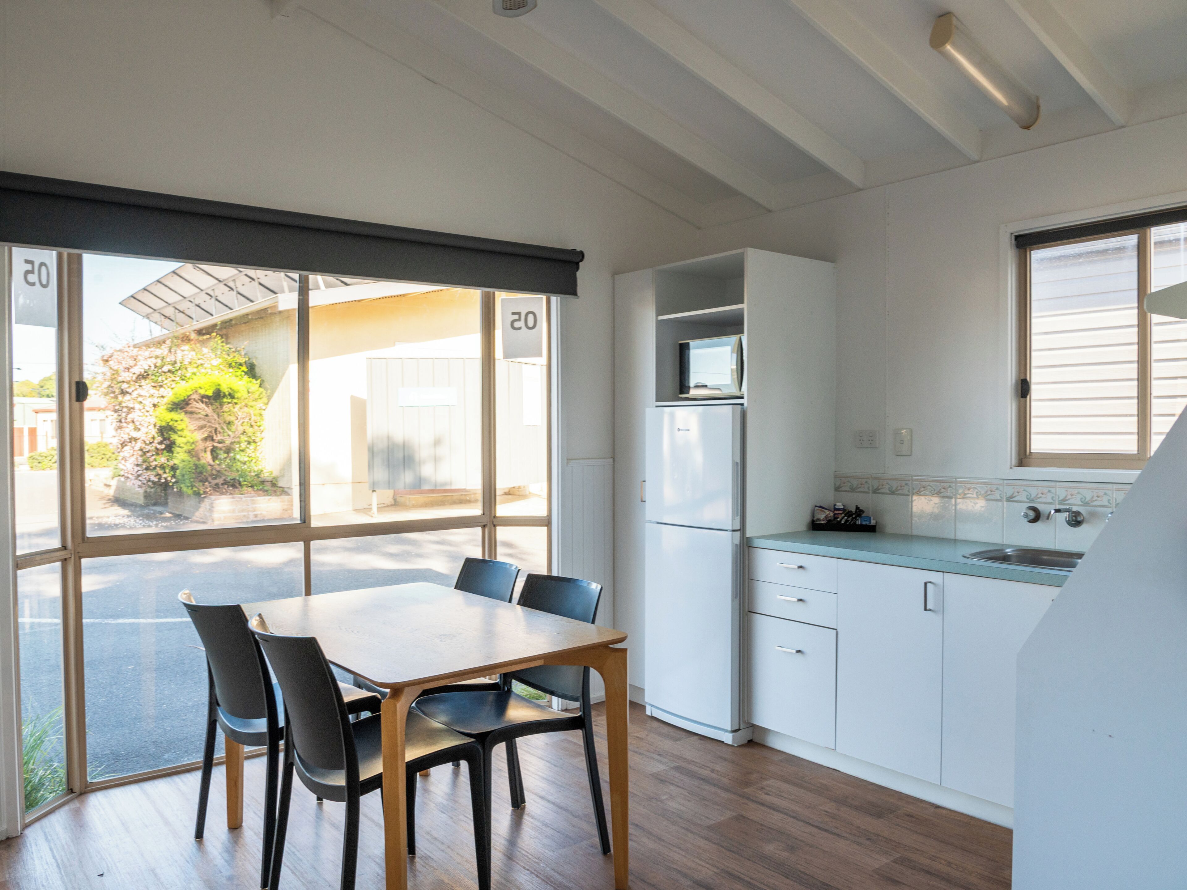Una cocina moderna con armarios blancos, una mesa de madera y sillas.