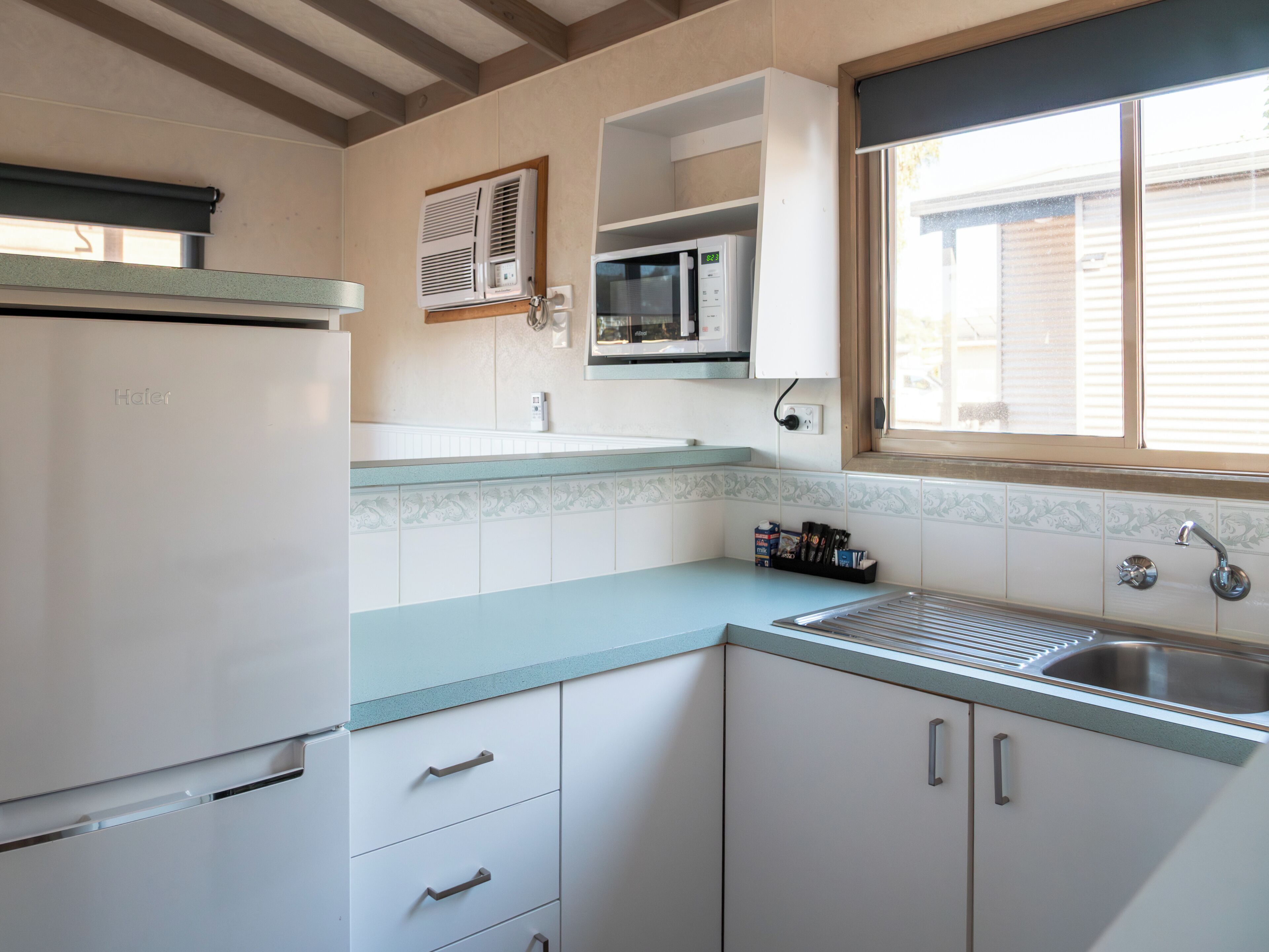 Una cocina equipada con refrigerador, microondas y lavamanos.