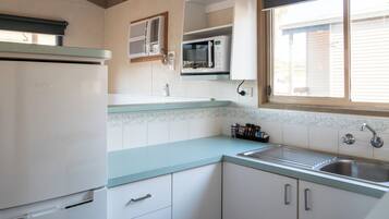 Una cocina equipada con refrigerador, microondas y lavamanos.
