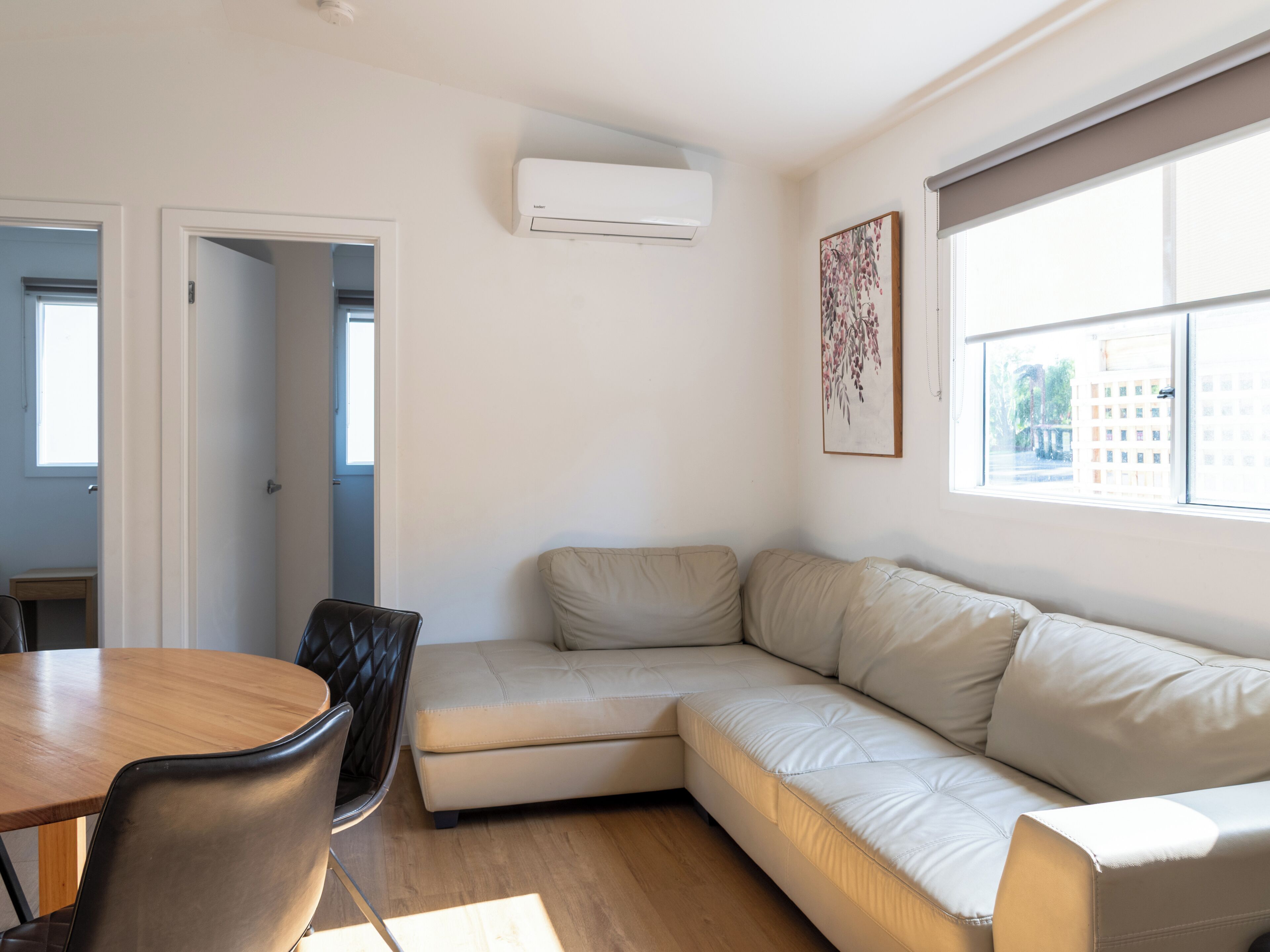 Una sala de estar moderna con un sofá seccional, una mesa de comedor con sillas y un ventanal grande.