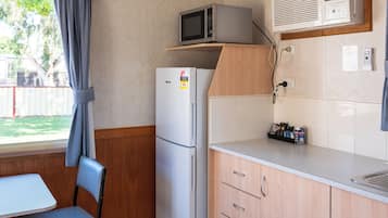 A compact kitchenette with a refrigerator, microwave, and a small countertop.