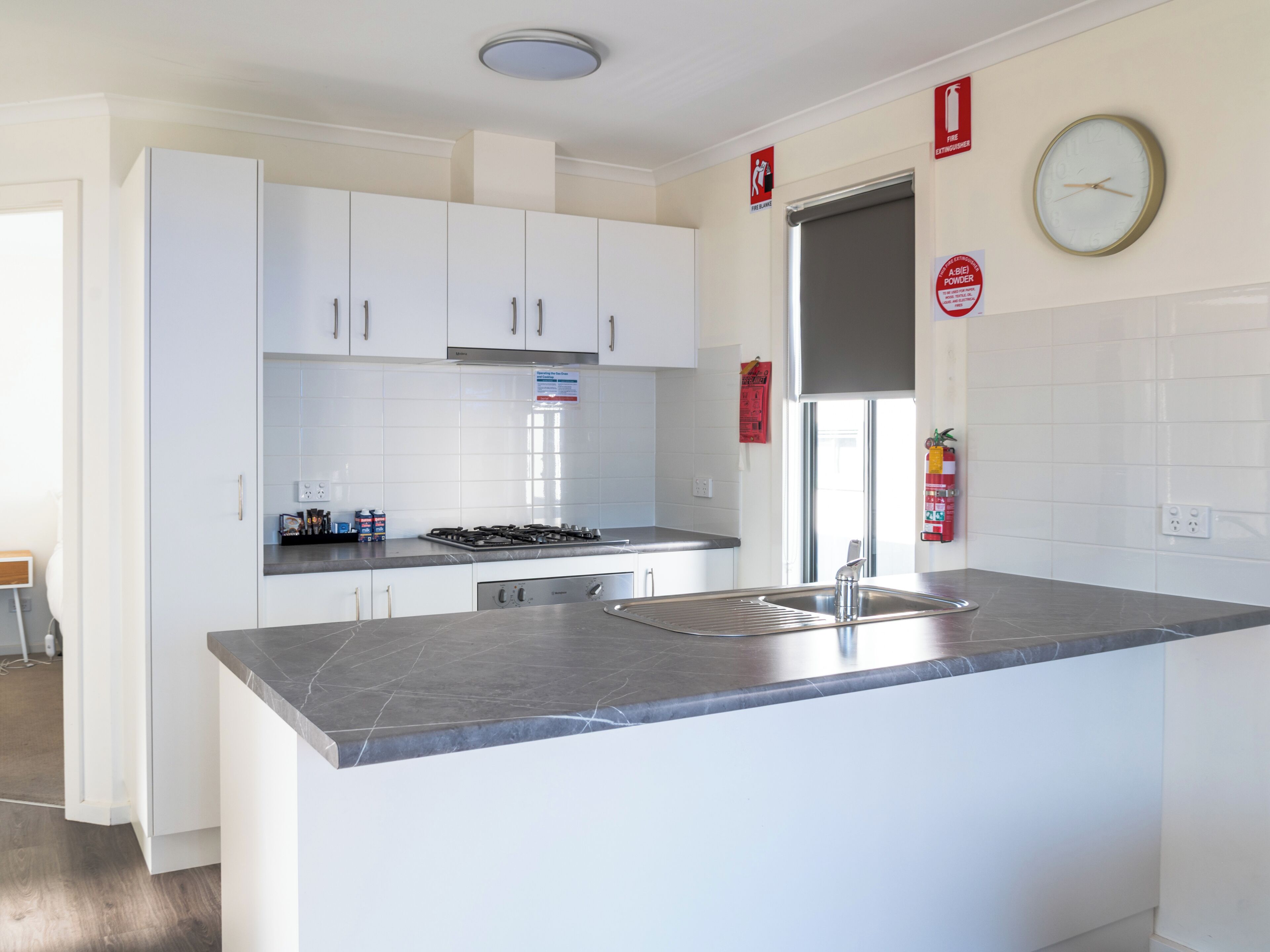 A modern kitchen with white cabinets, a stainless steel sink, and a built-in stove.