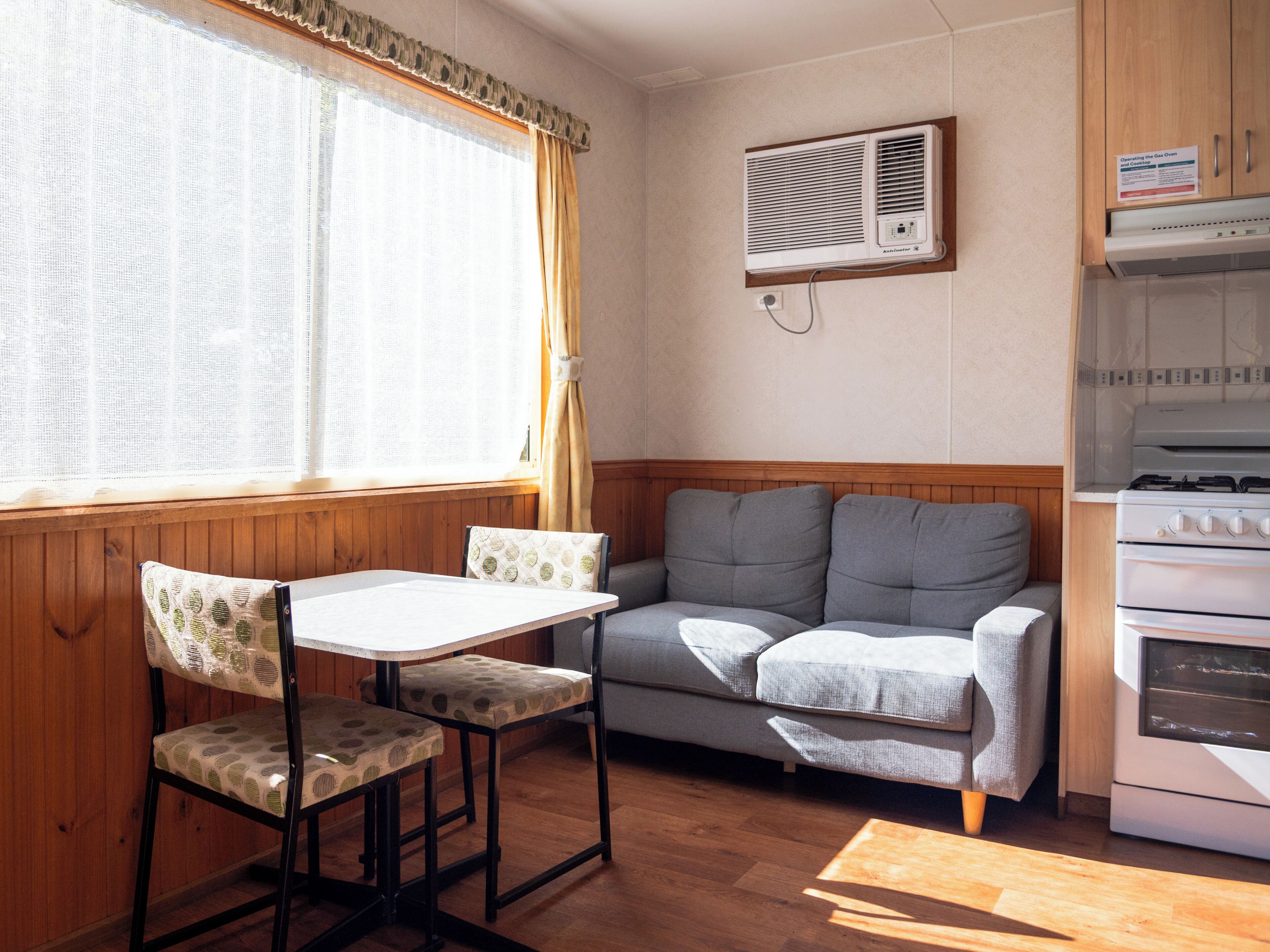 A compact kitchen with a gas stove, a built-in oven, and a window with curtains.