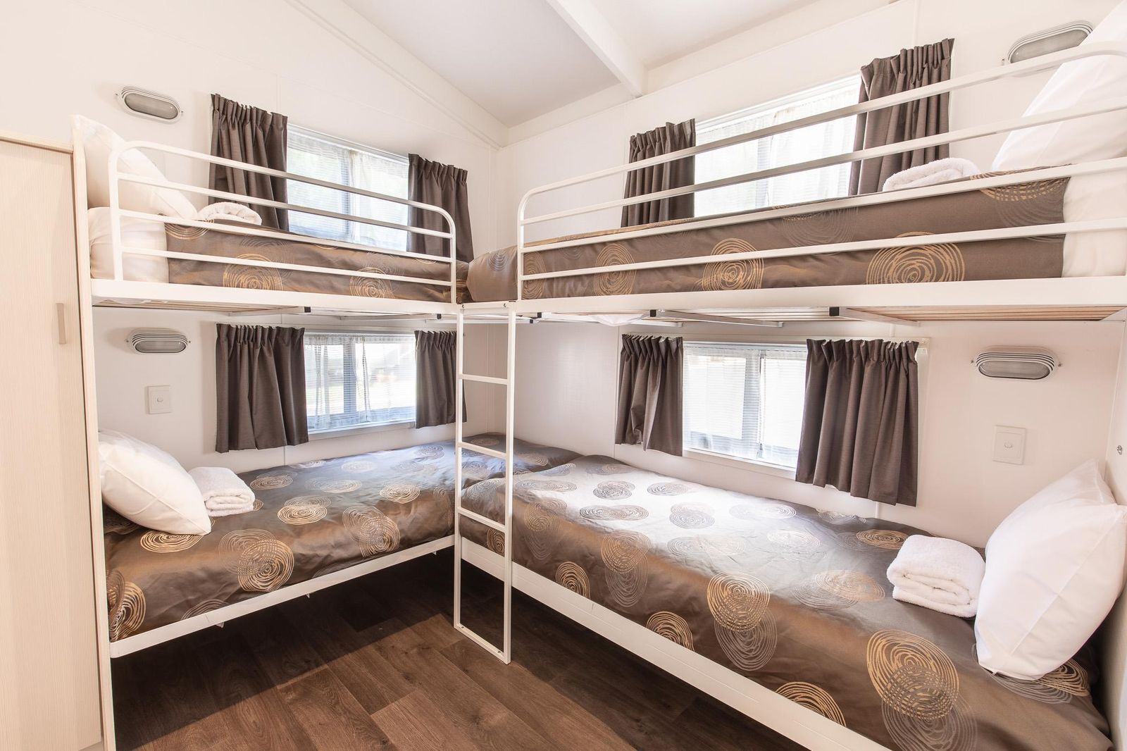 Een slaapzaal met vier bedden, elk met hoofdeinde en gordijnen.