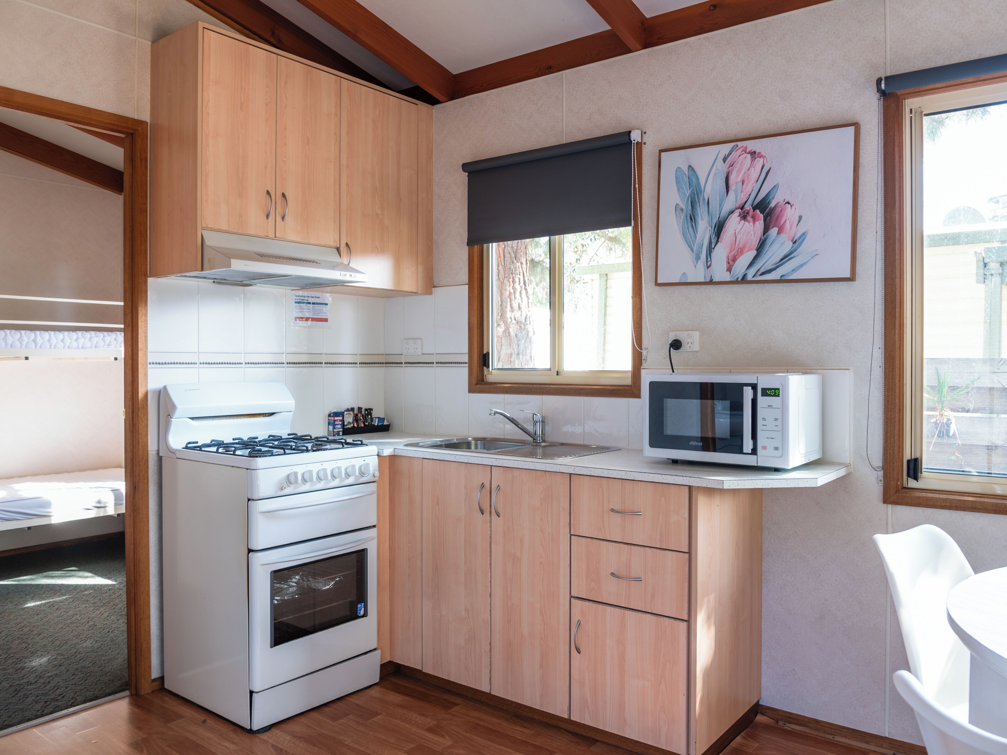 A compact kitchen with wooden cabinets, a gas stove, an oven, a microwave, and a window with a view.