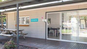 A building with a sign reading 'Camp Kitchen,' a picnic table, and a glass door entrance.