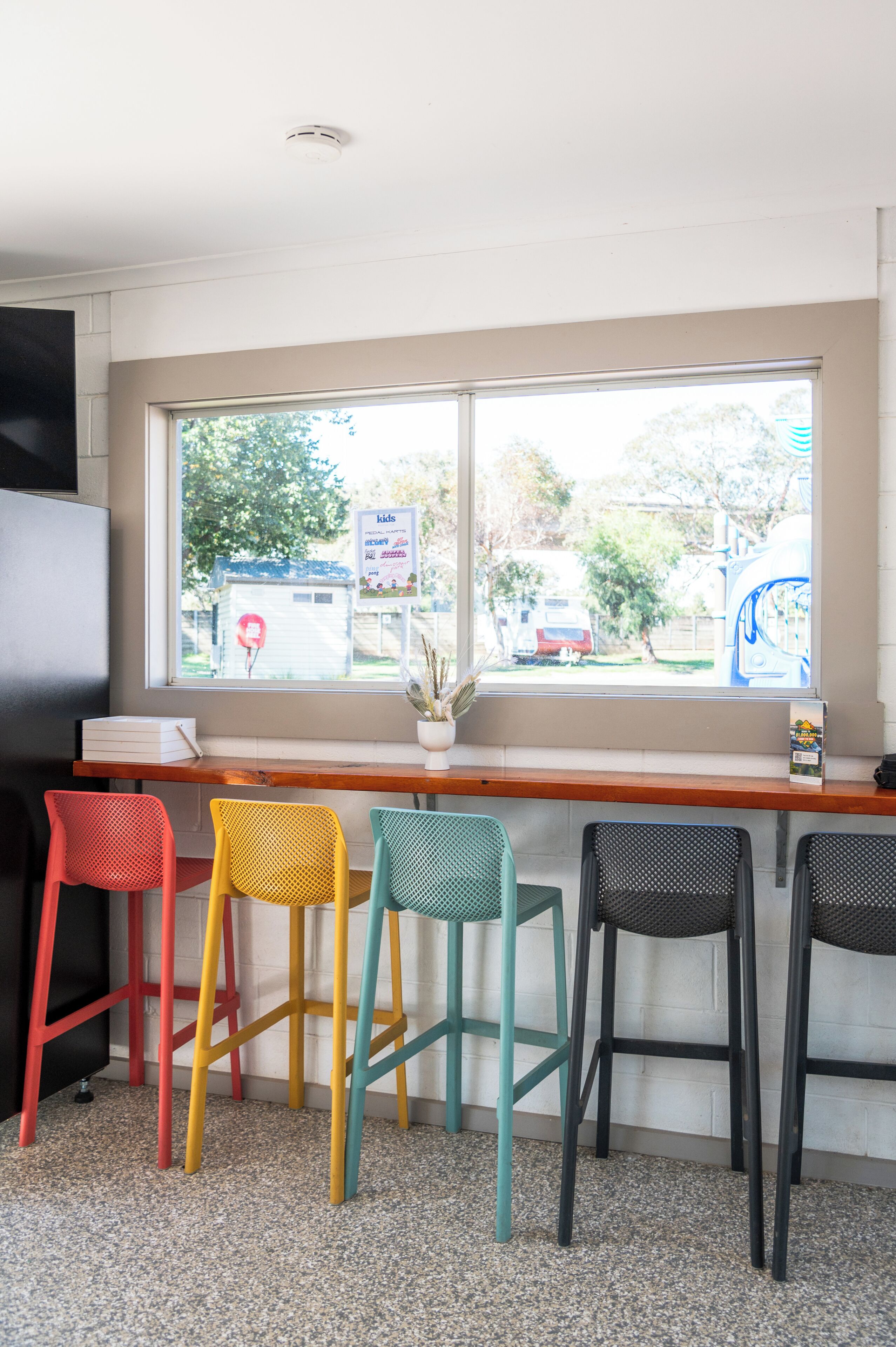 A seating area with colorful chairs and a window with a view of the outside.