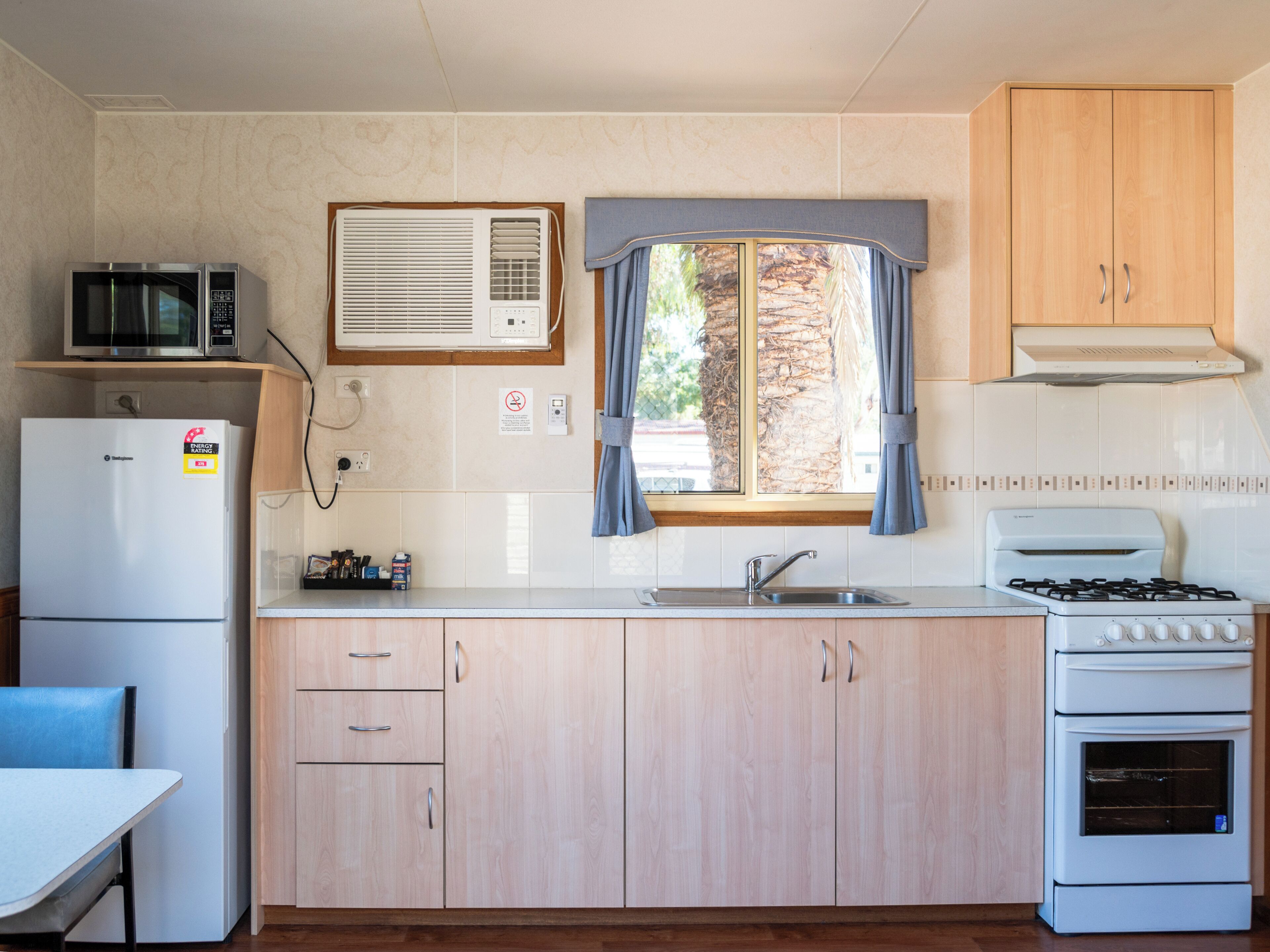 A compact kitchen with a refrigerator, microwave, stove, and sink.