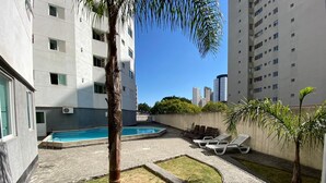 A residential building with a swimming pool, outdoor seating, and a palm tree. - B.Living (Curitiba)