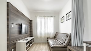 A modern living room with a sofa, TV, and wooden panel wall. - B.Living (Curitiba)