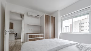 A modern bedroom with a bed, a desk, and a wardrobe. - B.Living (Curitiba)