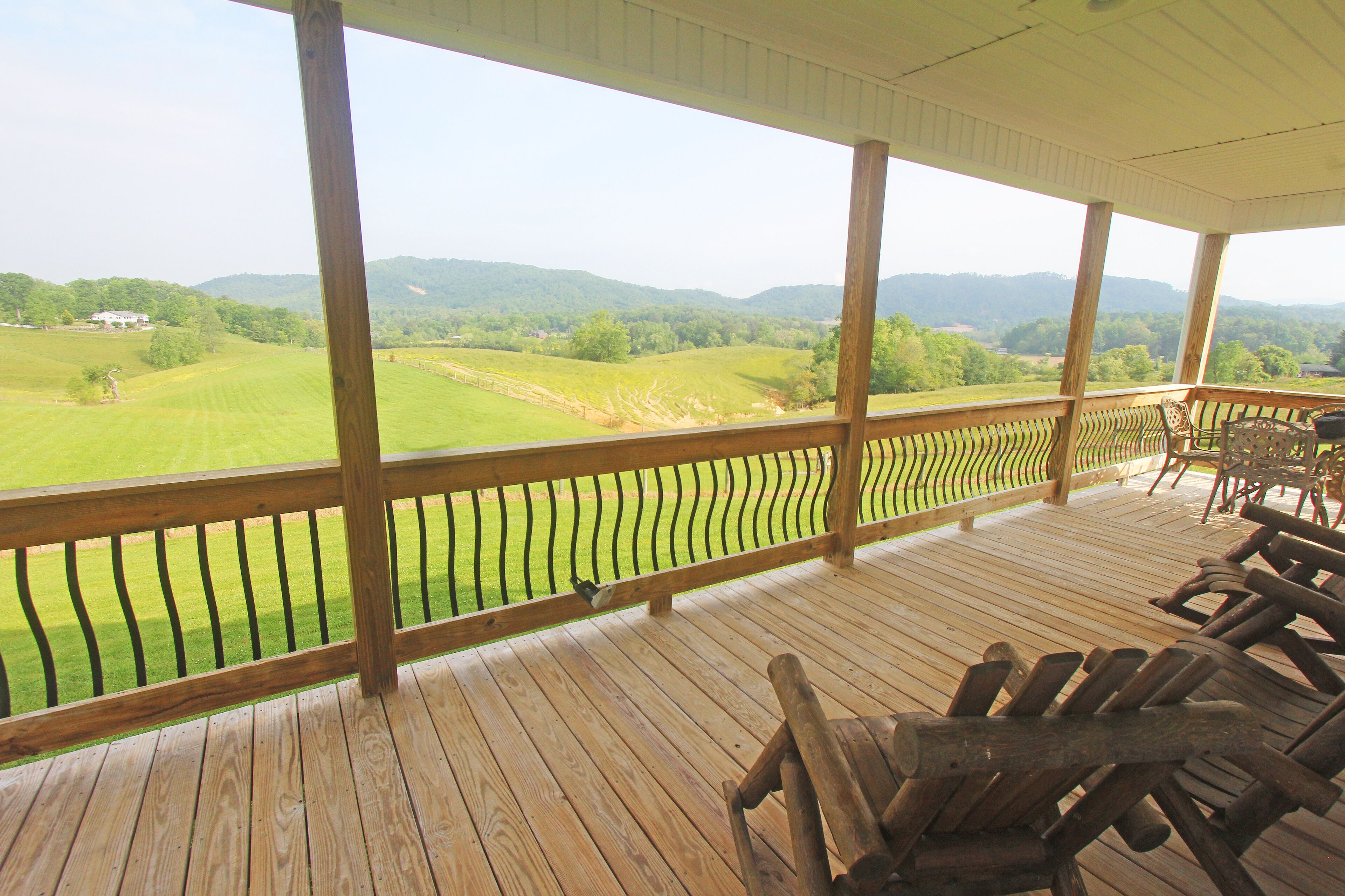 Una terraza de madera con vistas a un campo verde y montañas.