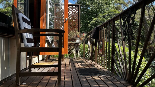 A wooden deck with a chair, a decorative fence, and a view of trees. - Blue Mountains studio, wild native garden full of birds, week-long stay 30% off (Hazelbrook)