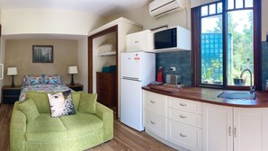 A compact kitchen with a microwave, refrigerator, and a window with a view of greenery. - Blue Mountains studio, wild native garden full of birds, week-long stay 30% off (Hazelbrook)