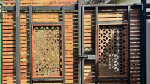 A wooden fence with a metal gate, a concrete pathway, and a small garden area with trees and flowers. - Blue Mountains studio, wild native garden full of birds, week-long stay 30% off (Hazelbrook)