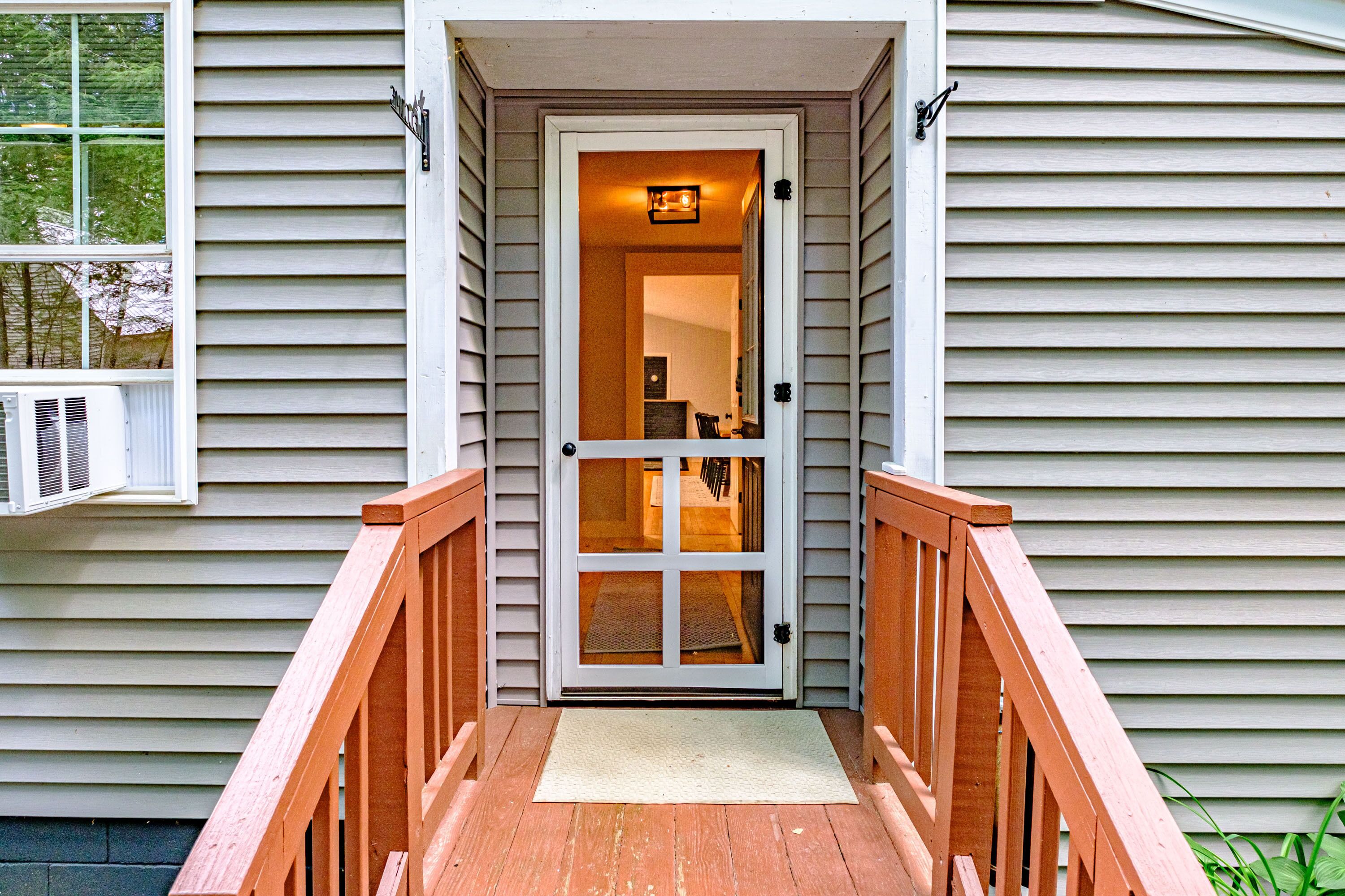 A wooden front porch with a white door and a small rug.