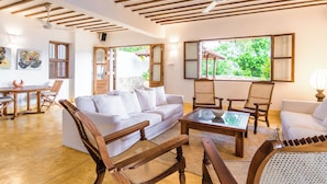 A spacious living area with a white sofa, wooden chairs, a coffee table, and a ceiling fan. - Cinnamon House by The Serendipity Collection (Weligama)